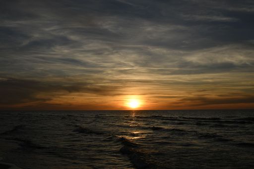 A serene sunset over the ocean with gentle waves and a dramatic sky.