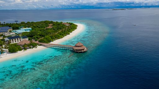 Aerial view of a tropical island resort with turquoise waters and lush greenery, showcasing a serene and picturesque coastal landscape.