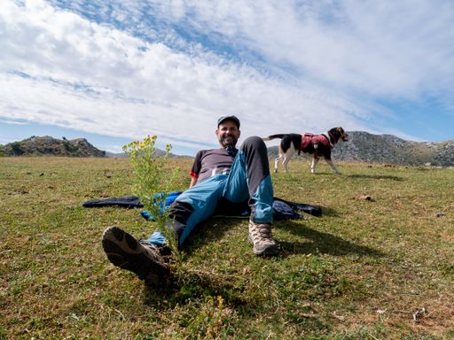 A Caucasian male with his dog relaxing in the mountains