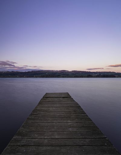 A vertical shot of a wooden dock on the sea in the evening