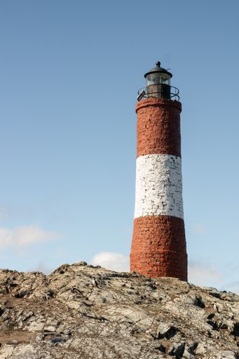 An eerie scenery of a lighthouse on the cliff on a sunny day