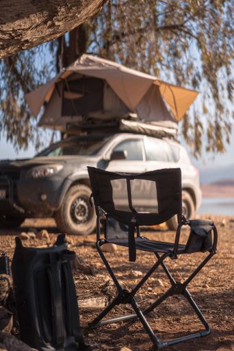 A view of a foldable chair and an SUV camper with rooftop tent in Morocco