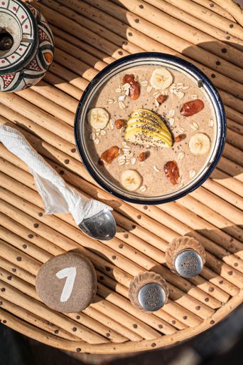 A top view closeup of typical Moroccan food bowl on a table with utensils and a stone with a number