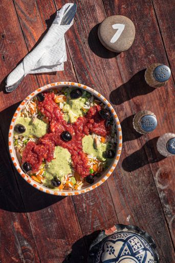 A top view closeup of a typical Moroccan food bowl, utensils and a stone with a number on it
