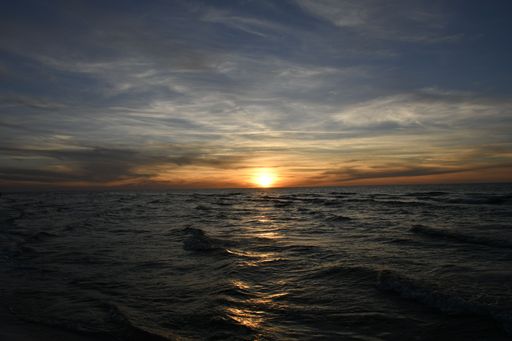 Serene sunset over the ocean with gentle waves and a dramatic sky, capturing the beauty of nature.