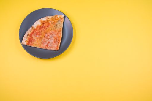 A plate with a slice of pizza isolated on a yellow background- free space for text