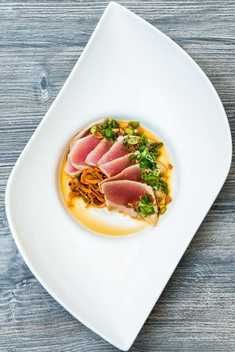 A vertical shot of a raw mat with sliced vegetables on top in a white modern plate