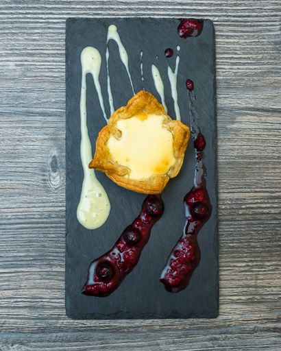 A vertical shot of a desert  with creams on a black tray on a wooden surface