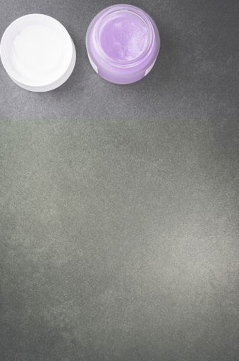 A top view of skin care cream container on a stone surface with free space for text