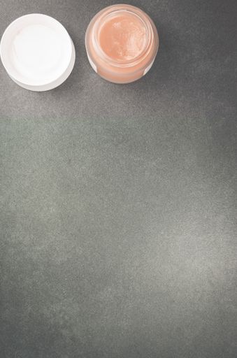 A top view of skin care cream container on a stone surface with free space for text