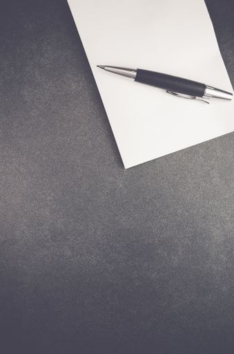 A paper and a pen isolated on a black background with free space for text
