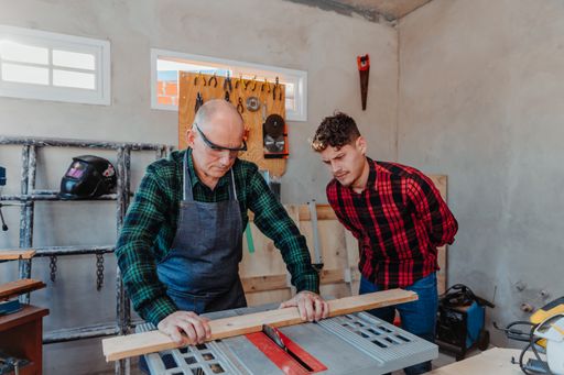 A senior carpenter teaching a younger man how to work