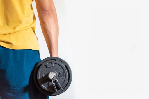 A male wearing sportswear holding a dumbbell isolated on a white background