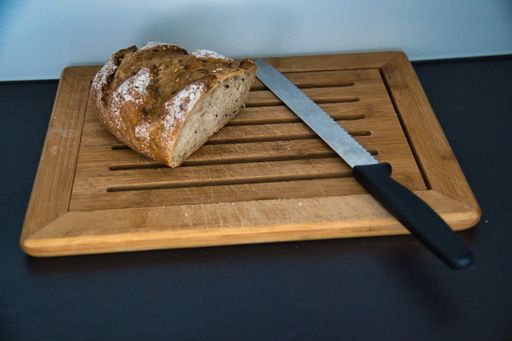 A closeup of a sliced fresh delicious bread on a wooden cutting board with a knife
