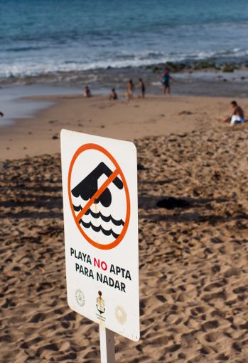 A vertical shot of the caution sign in the sandy beach