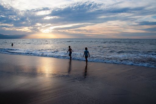 The children playing on the beach during sunset