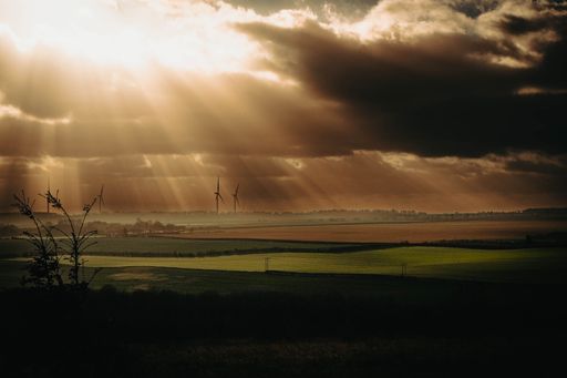 A scenic view of wind turbines on a vast landscape with dramatic sunlight breaking through clouds