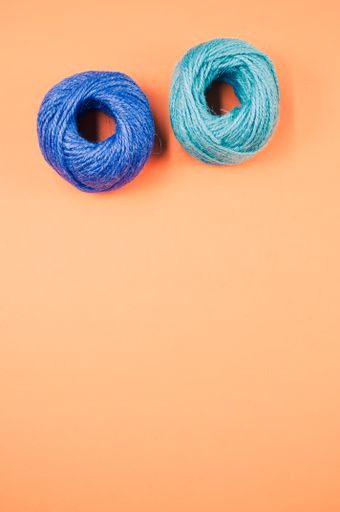 A top view of soft blue and green textile balls of wool on orange background with a copy space