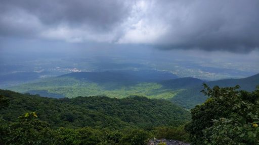 A scenic view of lush green hills under a cloudy sky, showcasing the beauty of nature
