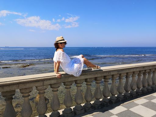 A woman lying on the handrails of the Mascagni Terrace and admiring the seascape in Livorno, Italy
