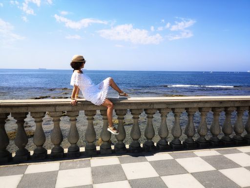 A woman lying on the handrails of the Mascagni Terrace and admiring the seascape in Livorno, Italy