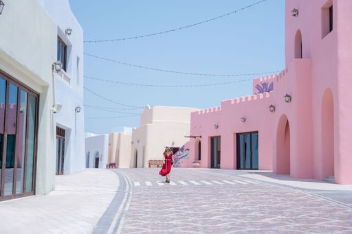 girl with a red dress walking on the Colorful Streets in Mina District Corniche, Doha Marina, Doha, Qatar