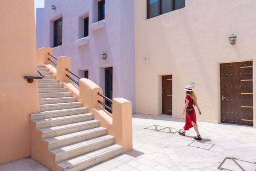 girl with a red dress walking on the Colorful Streets in Mina District Corniche, Doha Marina, Doha, Qatar