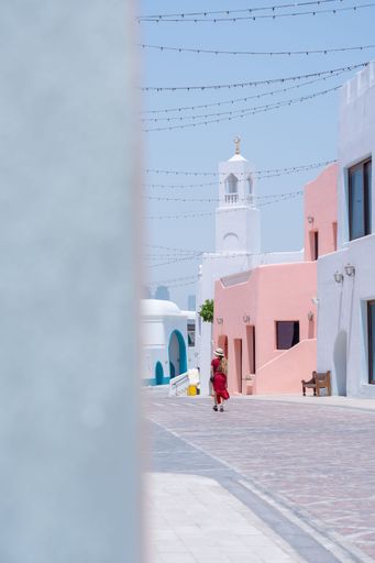 girl with a red dress walking on the Colorful Streets in Mina District Corniche, Doha Marina, Doha, Qatar