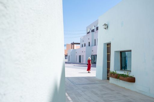 girl with a red dress walking on the Colorful Streets in Mina District Corniche, Doha Marina, Doha, Qatar