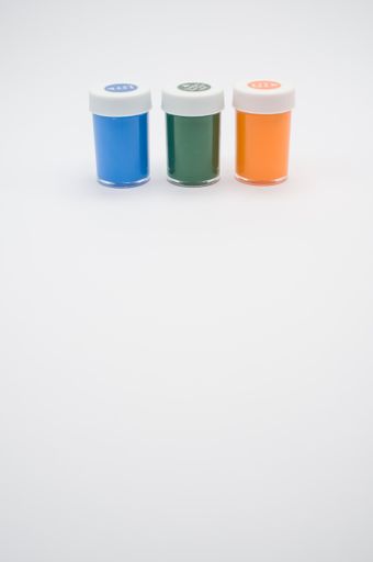 A top view of green, blue and orange gouache bottles isolated on white