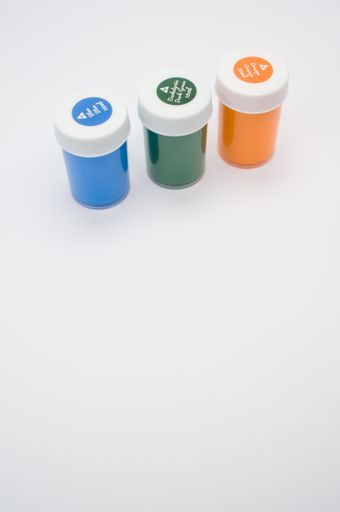 A top view of green, blue and orange gouache bottles isolated on white