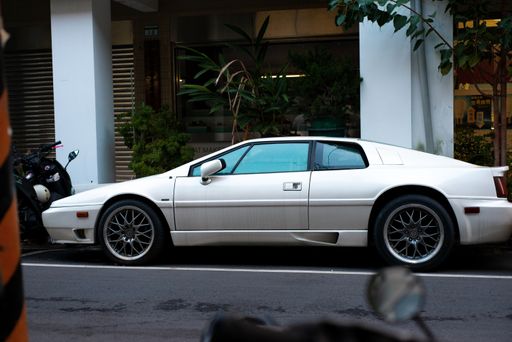 A white car parked in the street and a motorcycle near it