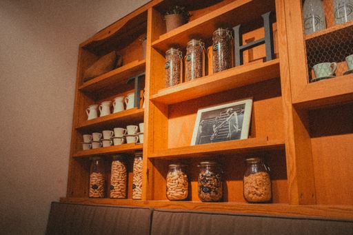 A  wooden cabinet filled with jars of nuts and coffee