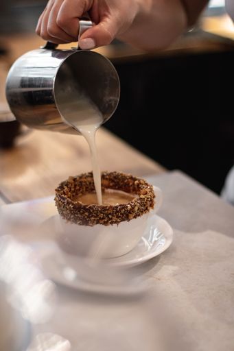 A vertical closeup shot of a barista making coffee with milk