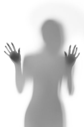 Silhouette of a person with hands pressed against a frosted glass surface, creating an abstract shadow effect.