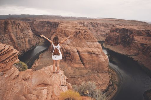 A woman standing on a cliff watching the landscape under the sky in Horseshoe Bend