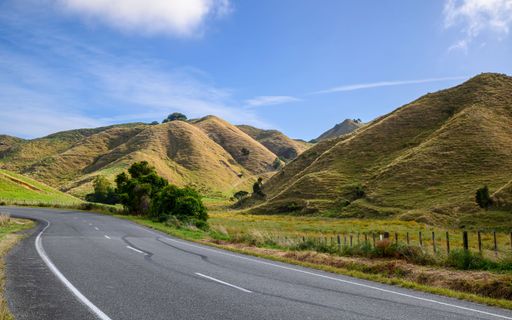A scenic view of a winding road through rolling green hills under a clear blue sky
