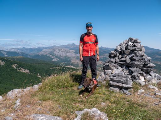 A closeup shot of a Caucasian male hiking in the mountains with his dog