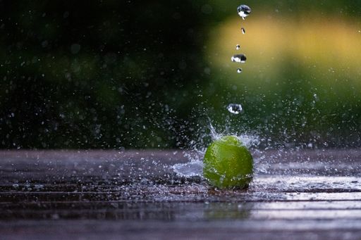 A closeup shot of a lime splashing onto a wet surface