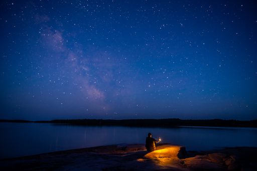A person resting on a beach under a starry galaxy sky
