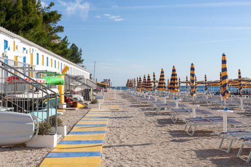 A sandy beach with closed umbrellas and chairs in the morning in Numana