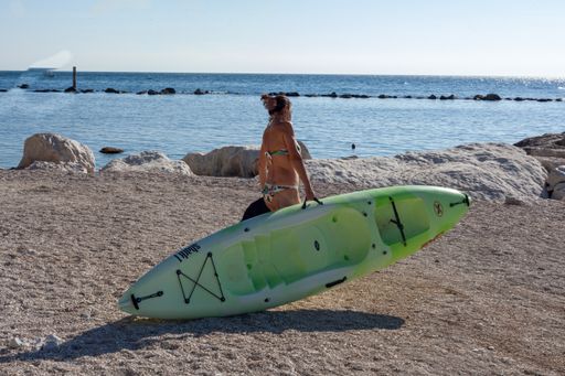 A woman on the Numana beach going to the sea with a small boat