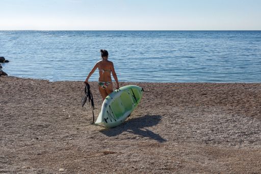 A woman on the Numana beach going to the sea with a small boat