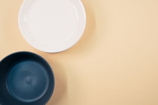 A top view of empty ceramic black and white plates on an orange background