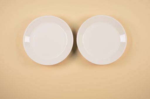 A top view of empty ceramic white plates on an orange background