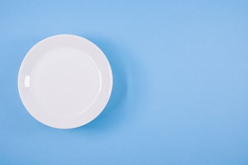 A top view of anempty ceramic white plates on a blue  background
