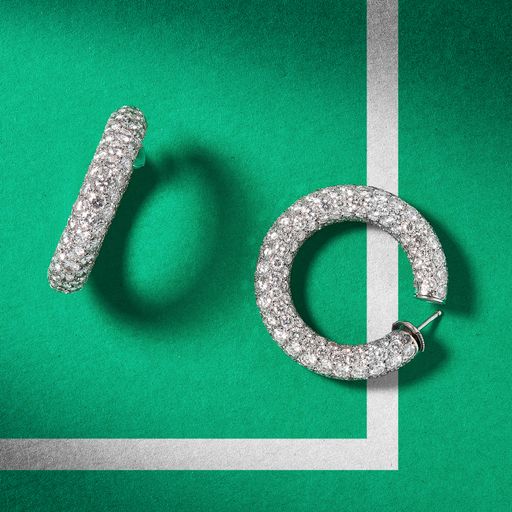 A high angle shot of a pair of beautiful diamond earrings on a green background