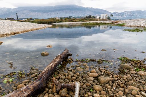 A lakeshore with stones and pebbles during the daytime