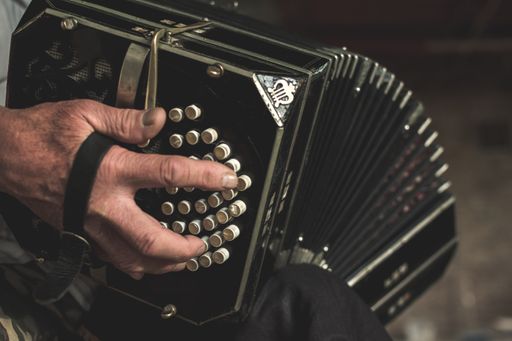 a closeup of a black bandoneon in the process of playing