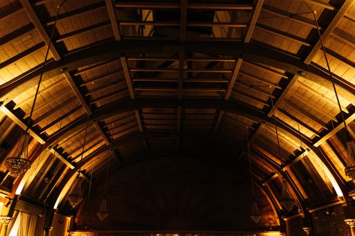 A wooden round ceiling of a dark room with chandeliers